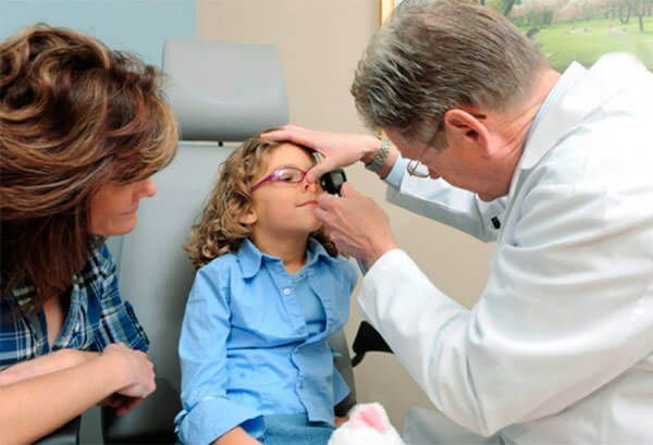 Доктор обследует ребенка с частым кровотечением из носа